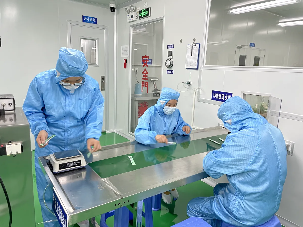 Operators checking single-dose oral care packs in a Fuzhou clean production area